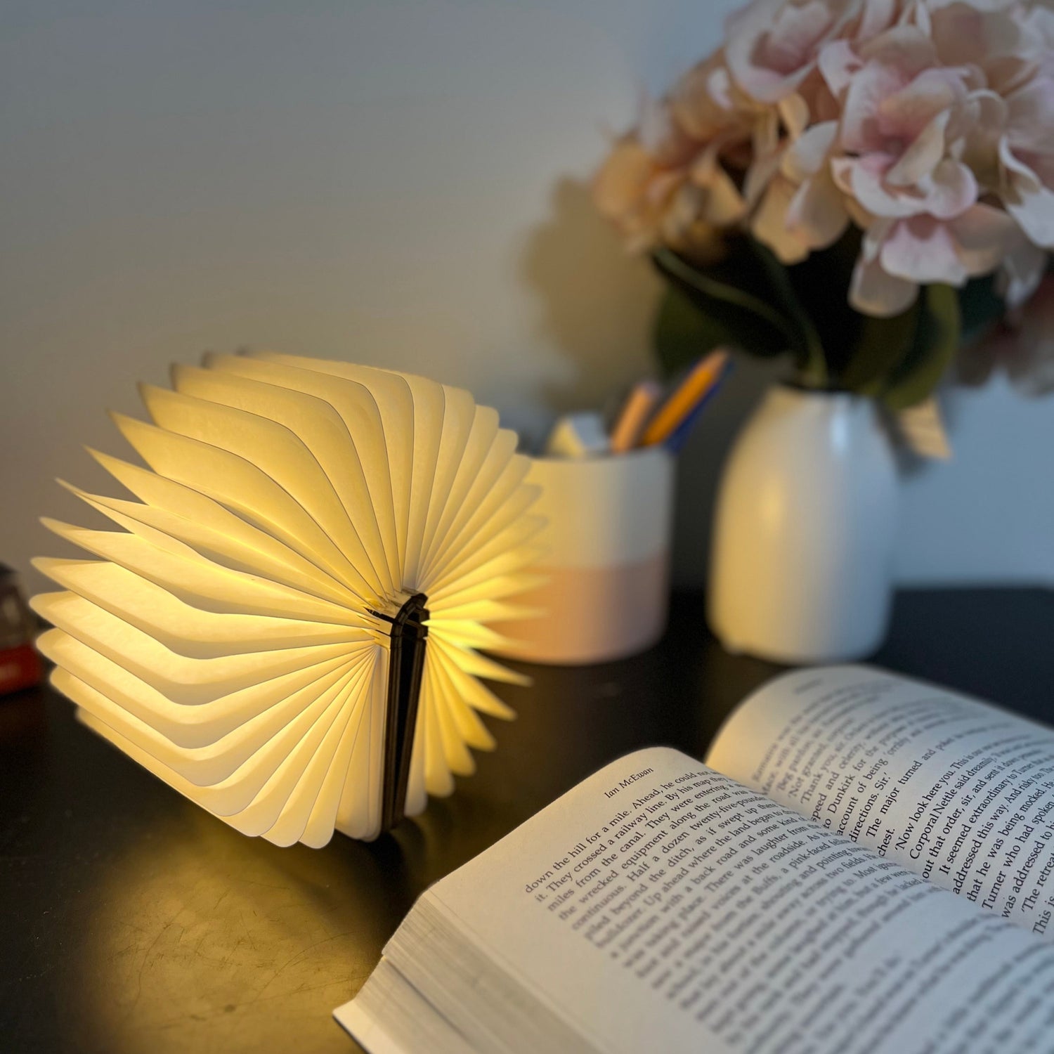 I Lumi Book glowing beside a book on a desk 